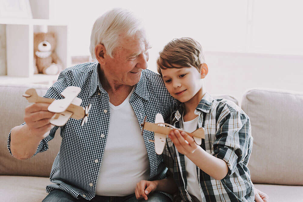 grandfather playing with his grandson with cardboard airplanes