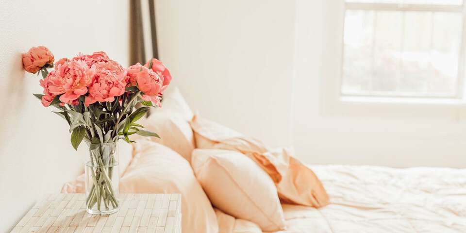 pink peonies next to bed