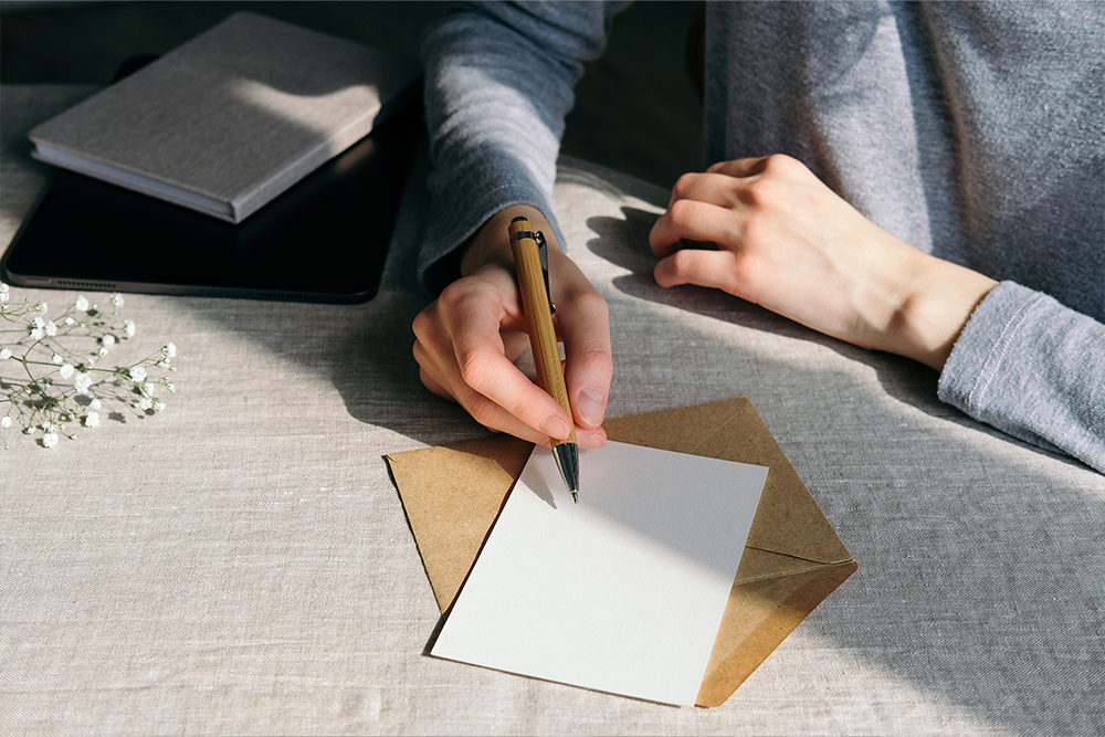 person holding pen about to write on a card