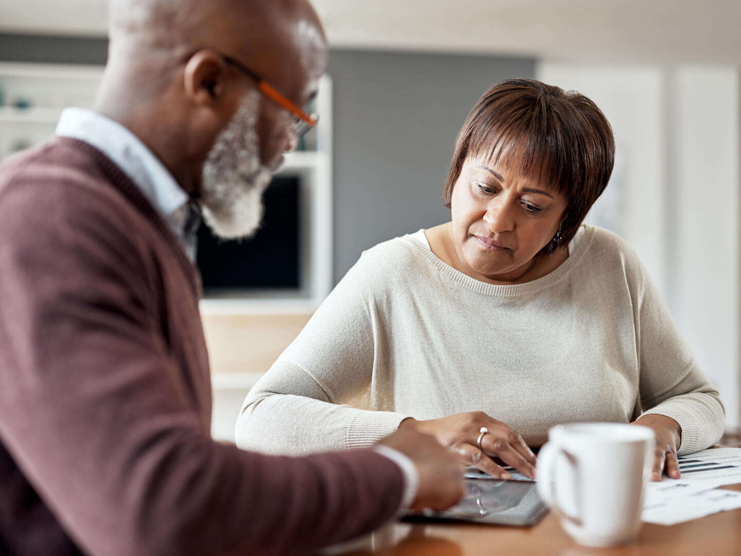 mature couple sitting at table looking at pictures papers