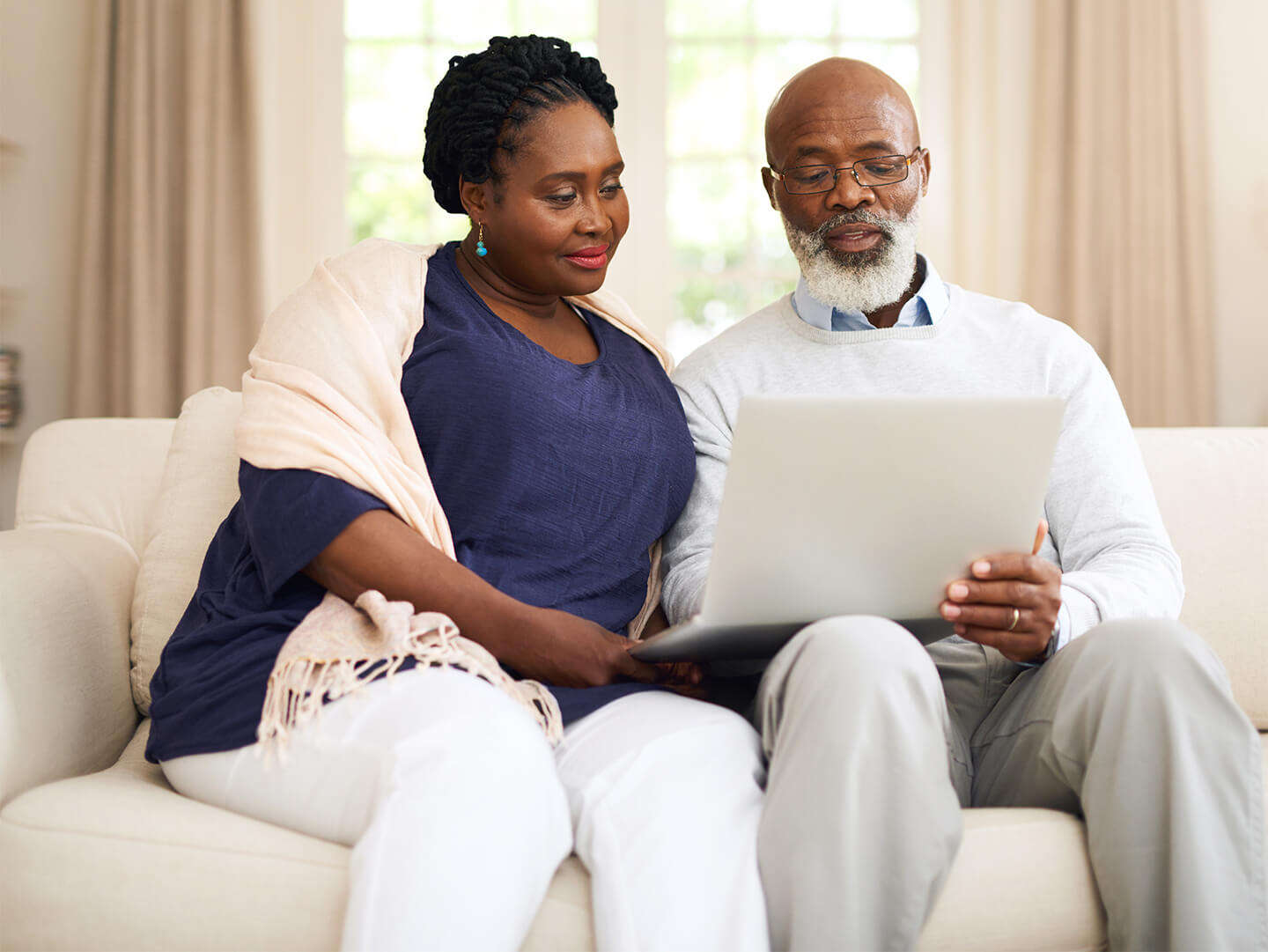 mature couple sitting on sofa looking at laptop computer